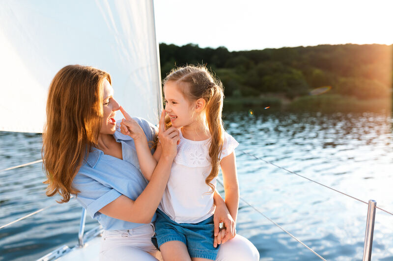 Mutter und Tochter auf einem Segelboot am See bei Sonnenuntergang